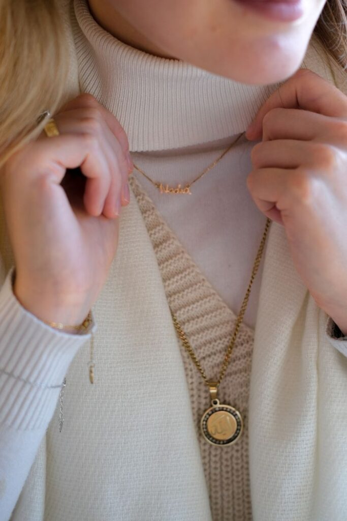 Home Close-up of a woman's neck adorned with gold necklaces and a beige turtleneck, showcasing elegant jewelry.